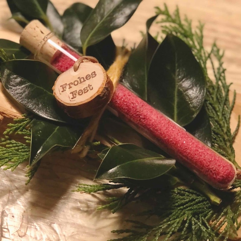 Das Bild zeigt ein Reagenzglas mit rotem Blütensalz und Holzanhänger Frohes Fest als Giveaway zu Weihnachten zum kaufen