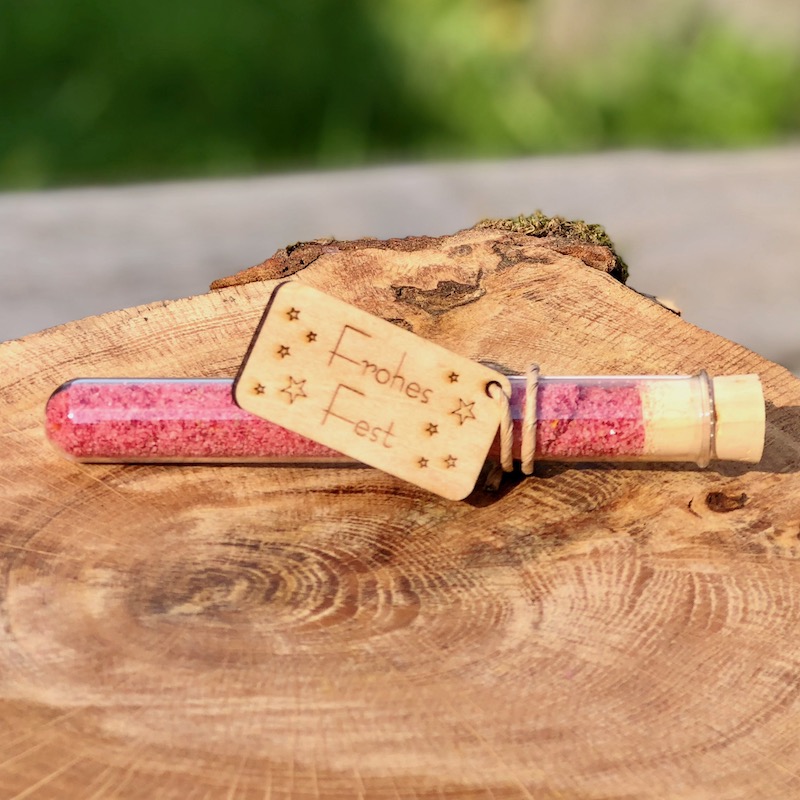 Giveaway Weihnachten Frohes Fest kaufen Das Bild zeigt ein Reagenzglas mit rotem Blütensalz und Holzanhänger Frohes Fest als Giveaway zu Weihnachten zum kaufen