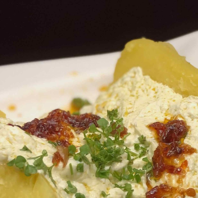 Heide Crunch Serviervorschlag Heidecrunch auf Pellkartoffel mit Quark und Gartenschaumkraut auf einem Teller als Serviervorschlag für das Crispy Chili Oil