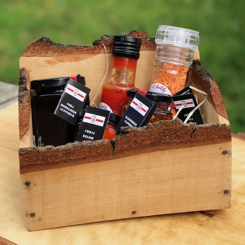 Chili Geschenkkiste Birkenholz Auf dem Bild ist ein Birkenholzkiste gefüllt mit unterschiedlichen Chiliprodukten