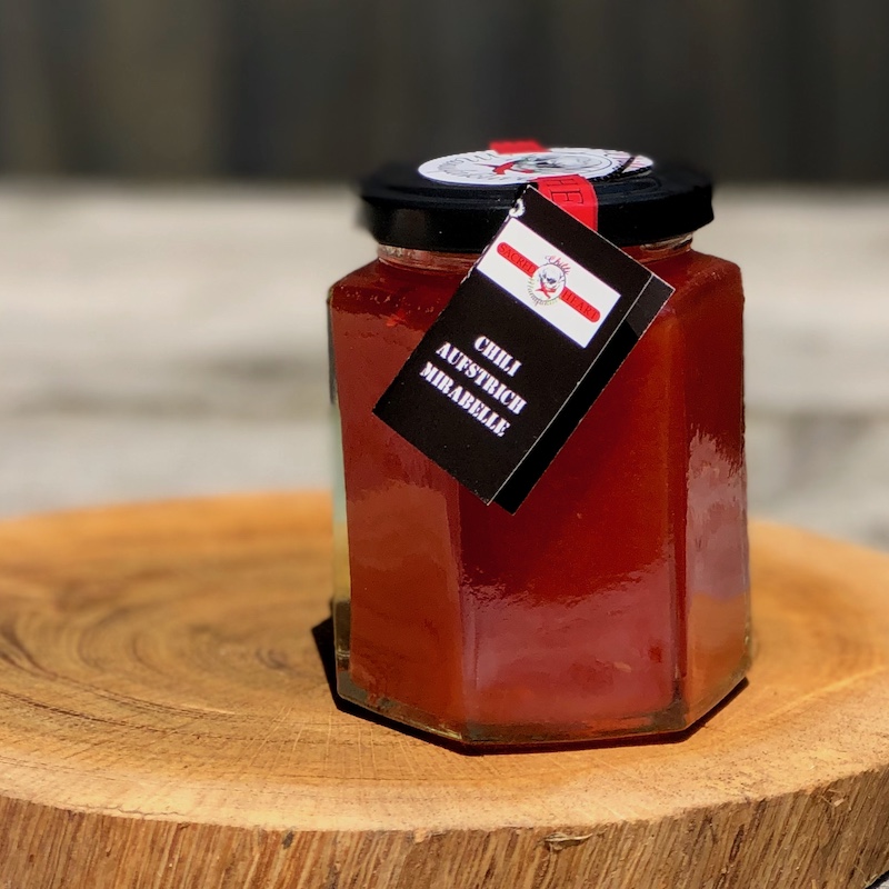 Ein Glas wilder Mirabellen Chili Aufstrich auf einer Holzscheibe stehend- wilde Mirabelle mit leichter Chilinote im Abgang