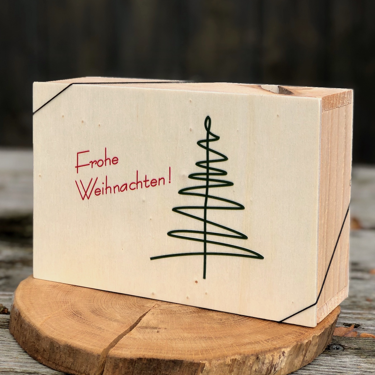 Geschenkbox Weihnachten Geschenkbox Weihnachten aus Holz mit Deckel und Beschriftung Frohe Weihnachten in rot mit grünen Tannenbaum als Strichzeichnung gefüllt mit Chiliöl, Käseheld und Aufstrich Frohe Weihnachten