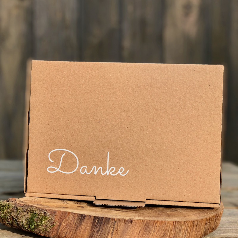 Geschenk Danke kaufen Geschenk Danke Geschenkbox mit der Aufschrift Danke in weiß und unterschiedlichen Chiliprodukten als Inhalt