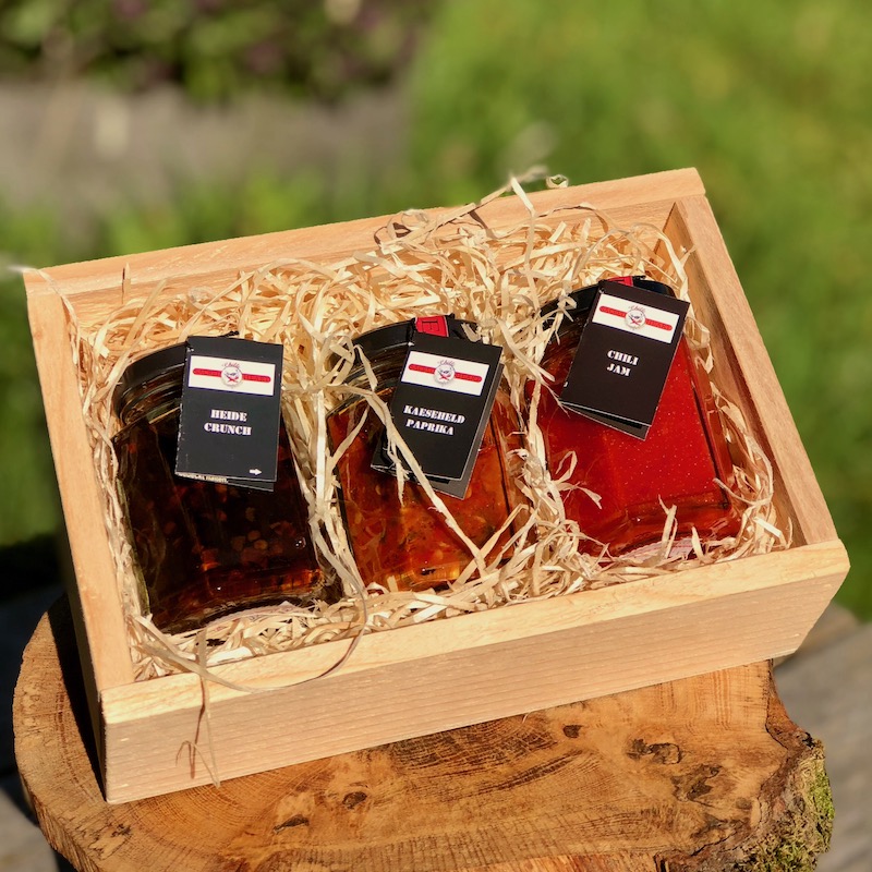 Scharfer Genuss Chili Geschenkbox Das Bild zeigt die Chili Geschekbox scharfer Genuss Inhalt ist Heide Crunch Käseheld und Chili Jam