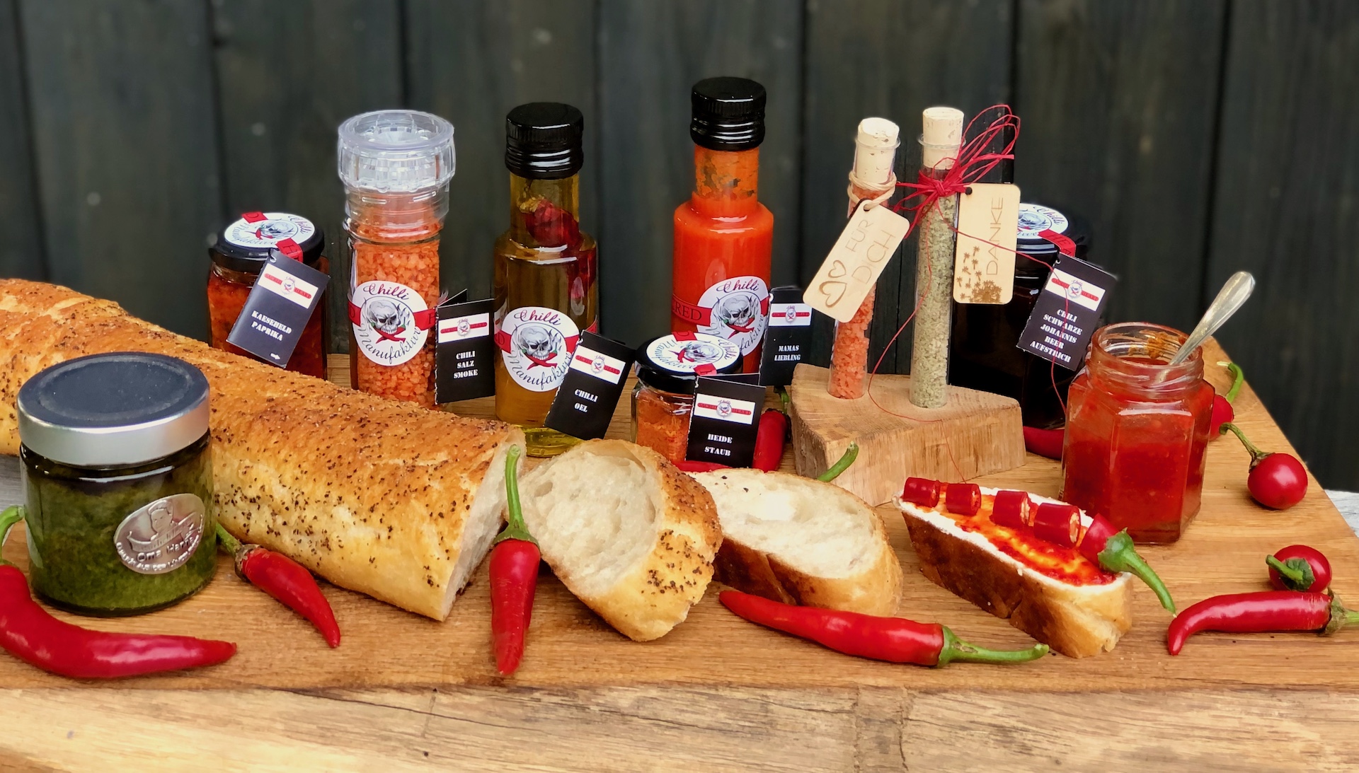 Prudukte von der Chilli Manufaktur auf einem Holzbrett mit frischem Brot und Chilischoten