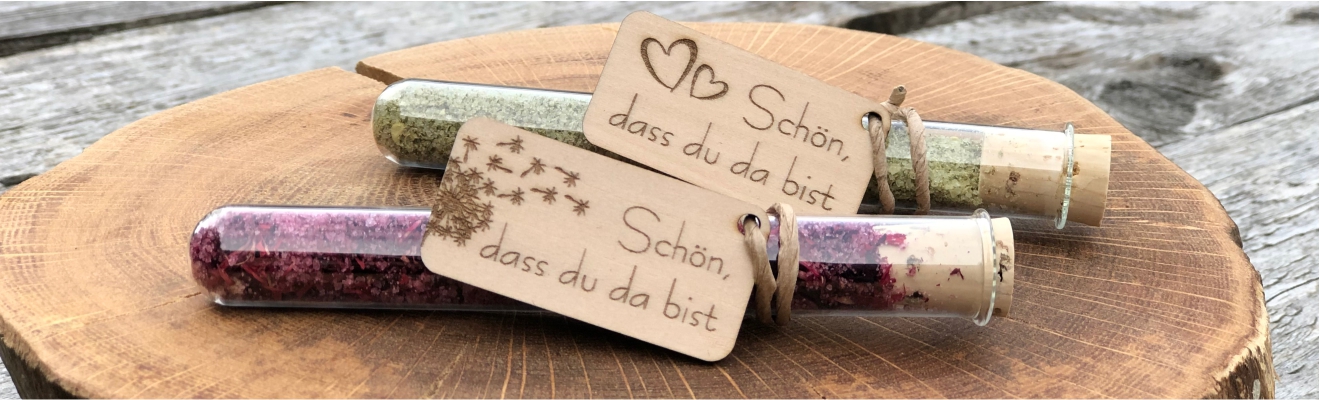 zwei kleine Gastgeschenke mit Salz im Reagenzglas und Anhänger aus Holz mit der Beschriftung Schön, dass du da bist als Gastgeschenk für Teammeeting Geburtstag Familienfeier