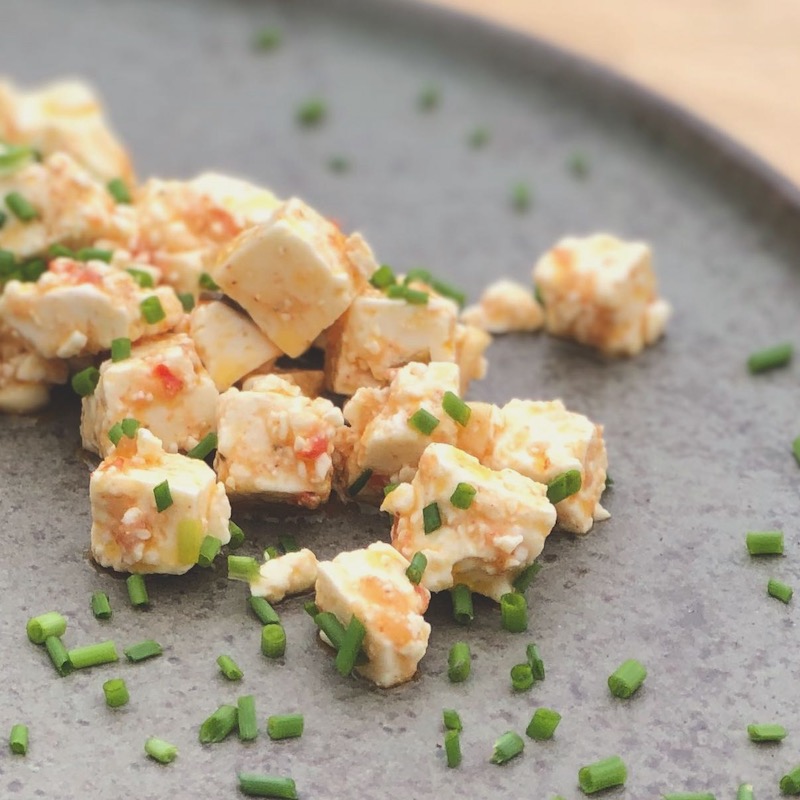 Eingelegter Feta mit Käseheld von der Chilli Manufaktur Das Bild zeigt eingelegten Feta mit Käseheld von der Chilli Manufaktur und Schnittlauchröllchen auf einem Teller